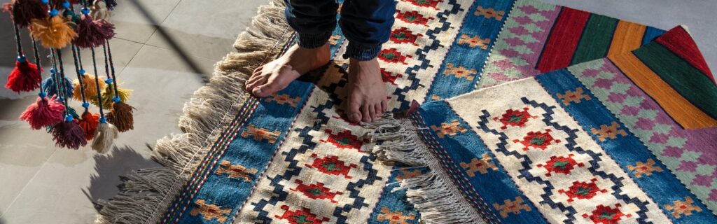 person in blue denim jeans standing on white blue and red area rug